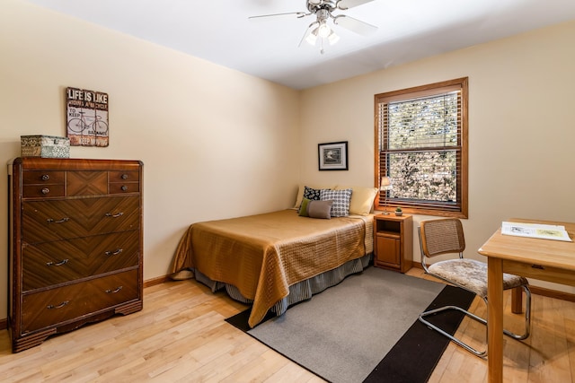 bedroom with light wood-style floors, ceiling fan, and baseboards