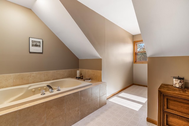 bathroom with lofted ceiling, a tub with jets, and baseboards