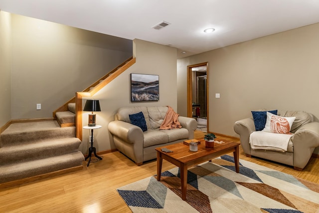 living room with light wood finished floors, stairway, visible vents, and baseboards