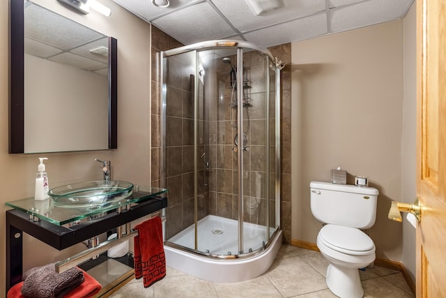 bathroom with a stall shower, baseboards, toilet, tile patterned flooring, and a sink