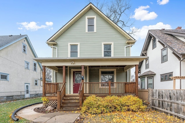 american foursquare style home featuring covered porch and fence