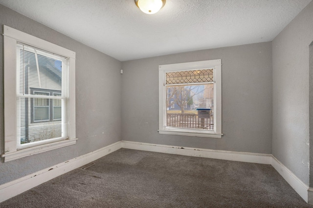 unfurnished room featuring a textured ceiling, carpet flooring, and baseboards