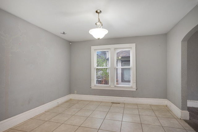 unfurnished room featuring arched walkways, baseboards, and light tile patterned floors