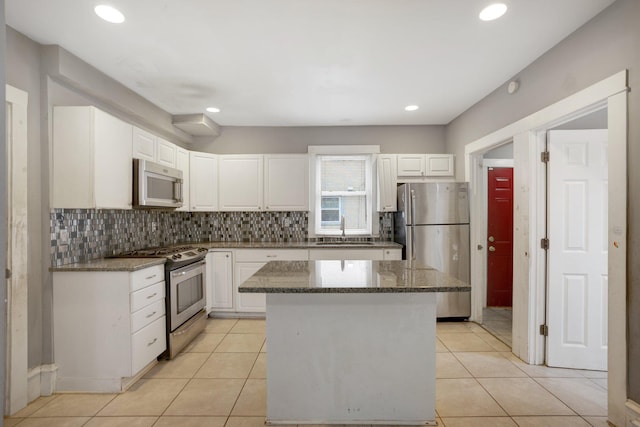 kitchen featuring light tile patterned floors, a kitchen island, stainless steel appliances, white cabinetry, and a sink