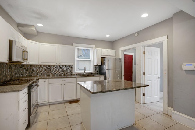 kitchen featuring appliances with stainless steel finishes, light tile patterned flooring, a sink, and decorative backsplash