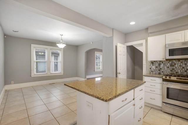 kitchen with light stone countertops, stainless steel range oven, a healthy amount of sunlight, and backsplash