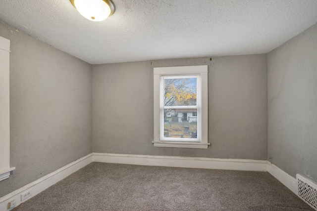 spare room with carpet floors, visible vents, a textured ceiling, and baseboards