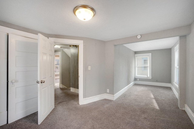 spare room with carpet floors, a textured ceiling, and baseboards