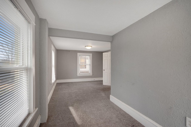 empty room featuring carpet flooring, a textured wall, and baseboards