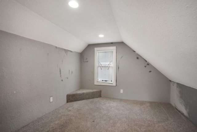 bonus room with a textured wall, carpet flooring, vaulted ceiling, and a textured ceiling