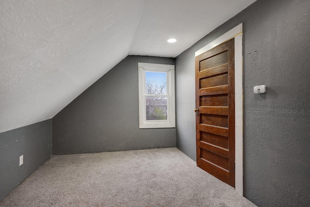 bonus room featuring carpet, vaulted ceiling, a textured wall, and a textured ceiling