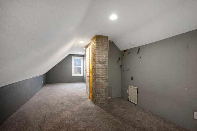 bonus room with carpet floors, decorative columns, vaulted ceiling, and a textured ceiling