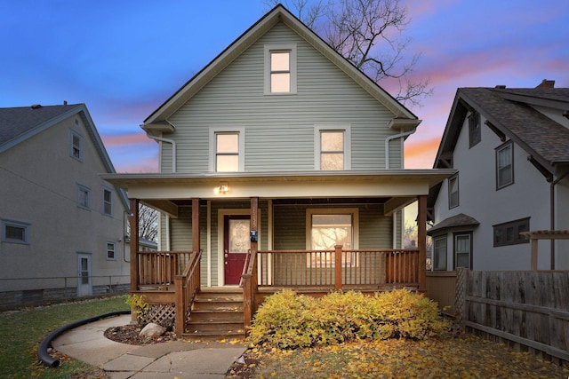 american foursquare style home featuring fence and a porch