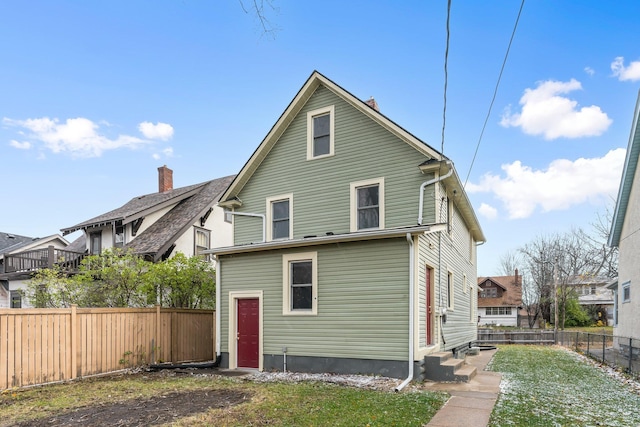 rear view of house featuring entry steps, a fenced backyard, and a yard