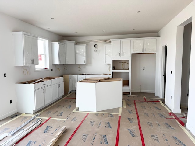 kitchen featuring white cabinetry, a kitchen island, and baseboards