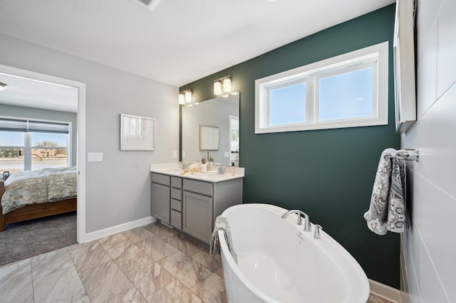 ensuite bathroom with marble finish floor, a freestanding bath, vanity, ensuite bath, and baseboards