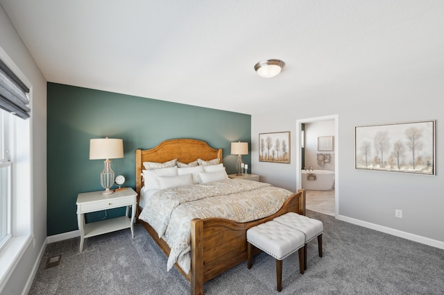 carpeted bedroom featuring ensuite bathroom, visible vents, and baseboards