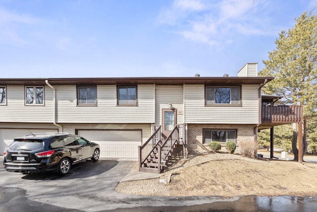 view of front of house featuring an attached garage, brick siding, driveway, and a chimney