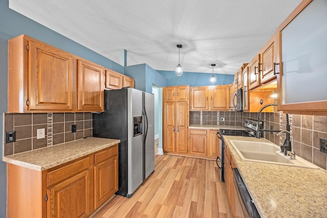 kitchen with appliances with stainless steel finishes, light countertops, lofted ceiling, and a sink