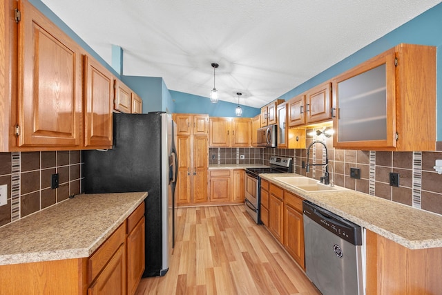 kitchen featuring light wood-type flooring, lofted ceiling, a sink, stainless steel appliances, and tasteful backsplash