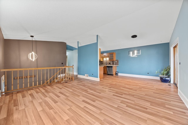 interior space featuring a sink, baseboards, lofted ceiling, and light wood-style flooring