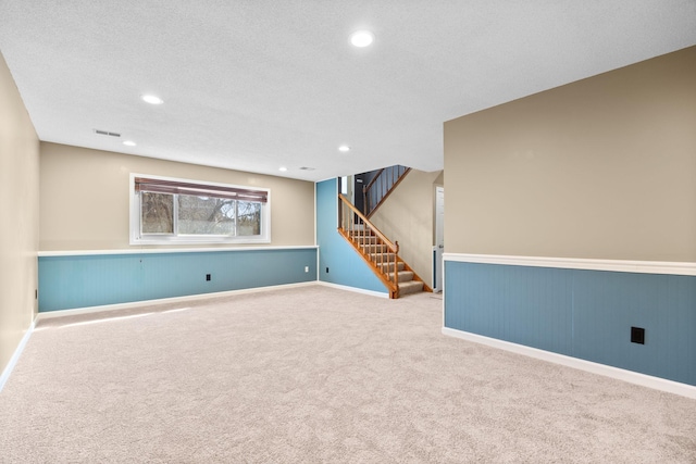 below grade area with visible vents, stairway, carpet floors, recessed lighting, and wainscoting