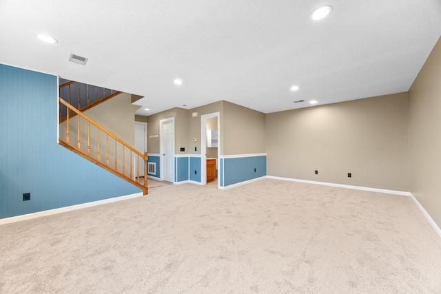 unfurnished living room with visible vents, baseboards, stairs, and carpet