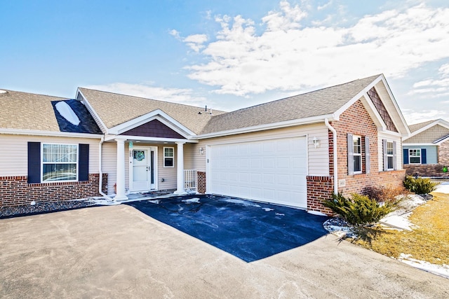 view of front facade with aphalt driveway, brick siding, a garage, and roof with shingles