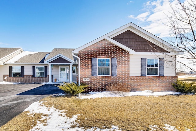 view of front of property featuring brick siding, a lawn, a shingled roof, and aphalt driveway