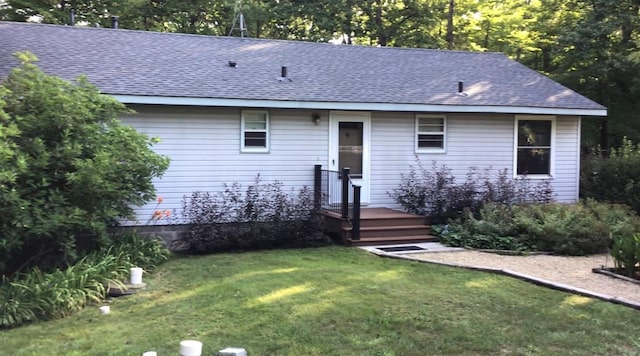 rear view of property featuring a yard and roof with shingles