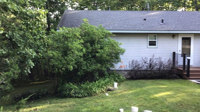 exterior space featuring a yard and a shingled roof