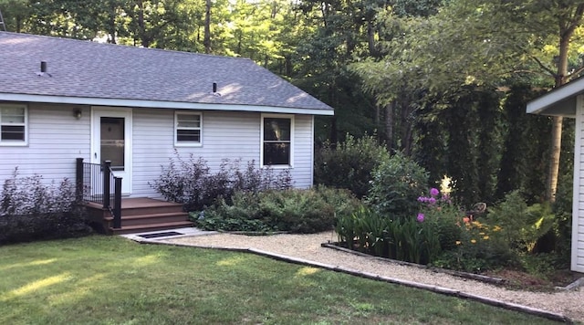 exterior space with roof with shingles and a front lawn