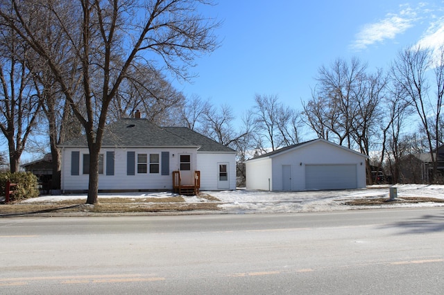 view of front of home with a shingled roof, an outbuilding, a detached garage, and a chimney