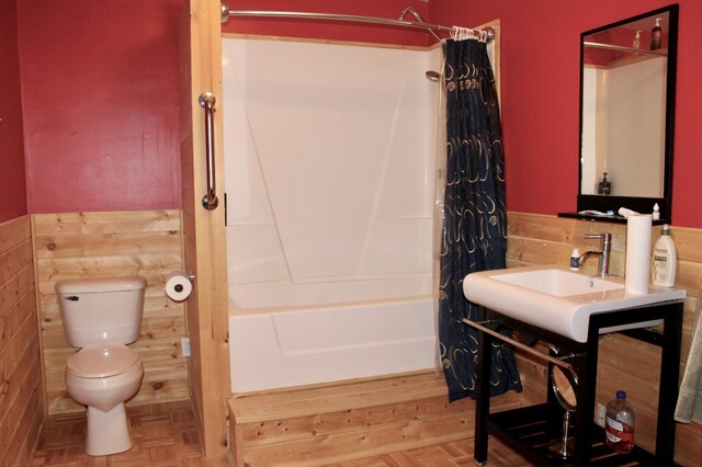 bathroom featuring toilet, a wainscoted wall, and shower / tub combo with curtain