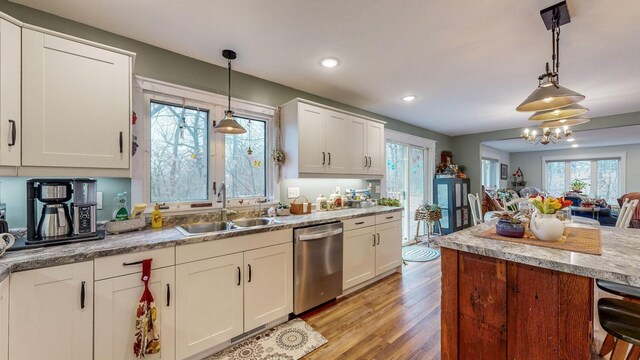 kitchen with pendant lighting, light wood finished floors, white cabinets, a sink, and dishwasher