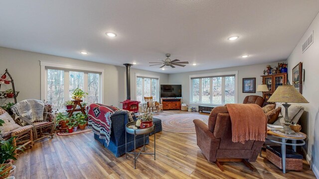 living room with recessed lighting, a wood stove, visible vents, and wood finished floors