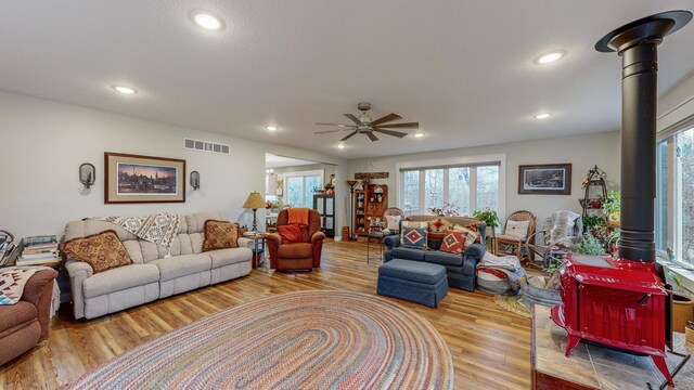 living area with recessed lighting, visible vents, a wood stove, ceiling fan, and wood finished floors