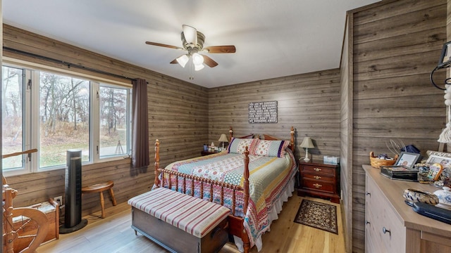 bedroom with wood walls, light wood-type flooring, and a ceiling fan