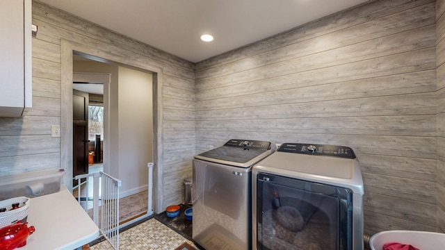 laundry room with laundry area, wood walls, and washing machine and clothes dryer