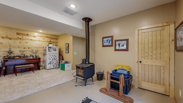 interior space featuring recessed lighting, visible vents, a wood stove, carpet flooring, and wooden walls