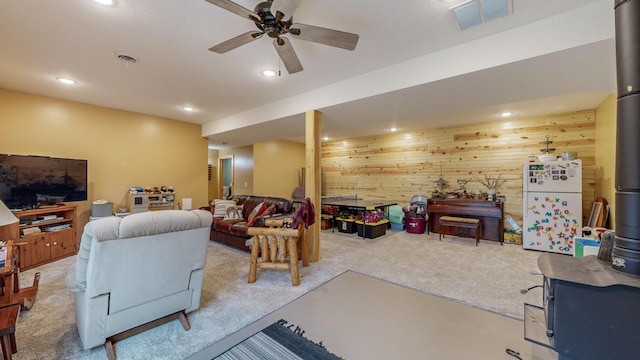 carpeted living room featuring a ceiling fan, recessed lighting, visible vents, and wooden walls