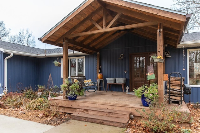 view of exterior entry featuring a shingled roof, board and batten siding, and a porch