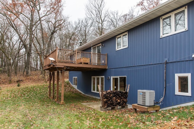 exterior space with a lawn, a wooden deck, and central air condition unit