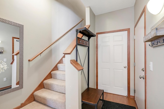 foyer entrance featuring stairway, wood finished floors, and baseboards