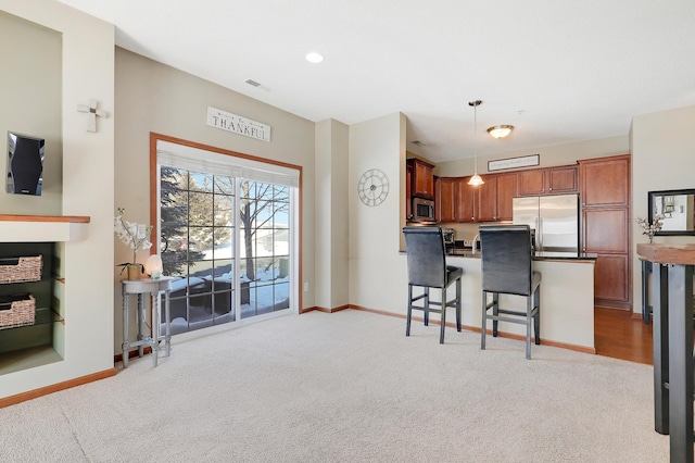 kitchen featuring light carpet, baseboards, a breakfast bar area, stainless steel appliances, and pendant lighting