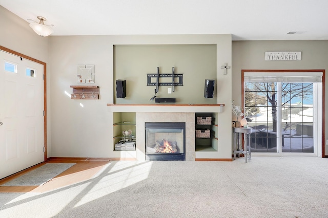 unfurnished living room with a tile fireplace, carpet flooring, and baseboards