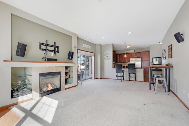 living room with recessed lighting, baseboards, a tiled fireplace, and light colored carpet