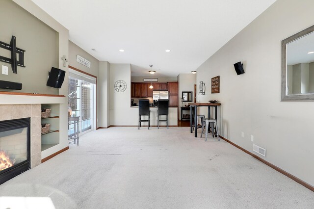 living room with light carpet, baseboards, a fireplace, and visible vents