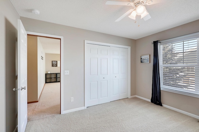 unfurnished bedroom featuring carpet, a textured ceiling, baseboards, and a closet