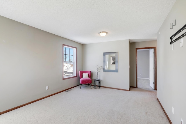 unfurnished room with light carpet, a textured ceiling, visible vents, and baseboards